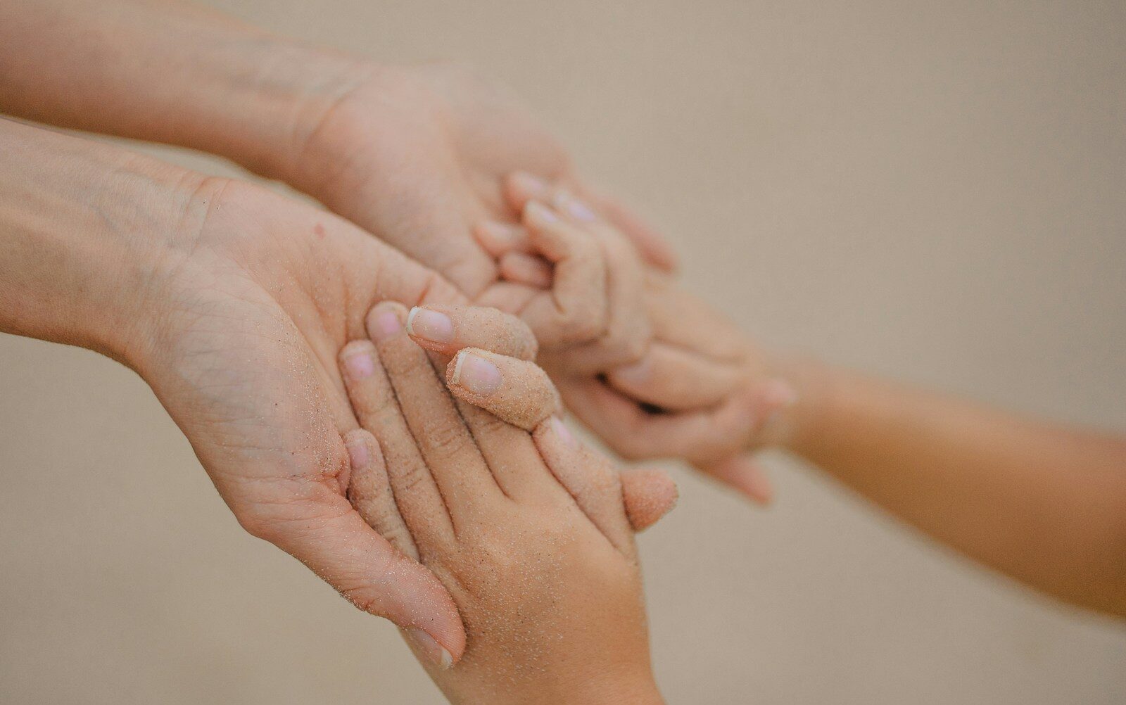 Praktiske oplysninger Adult and child hands gently holding each other.